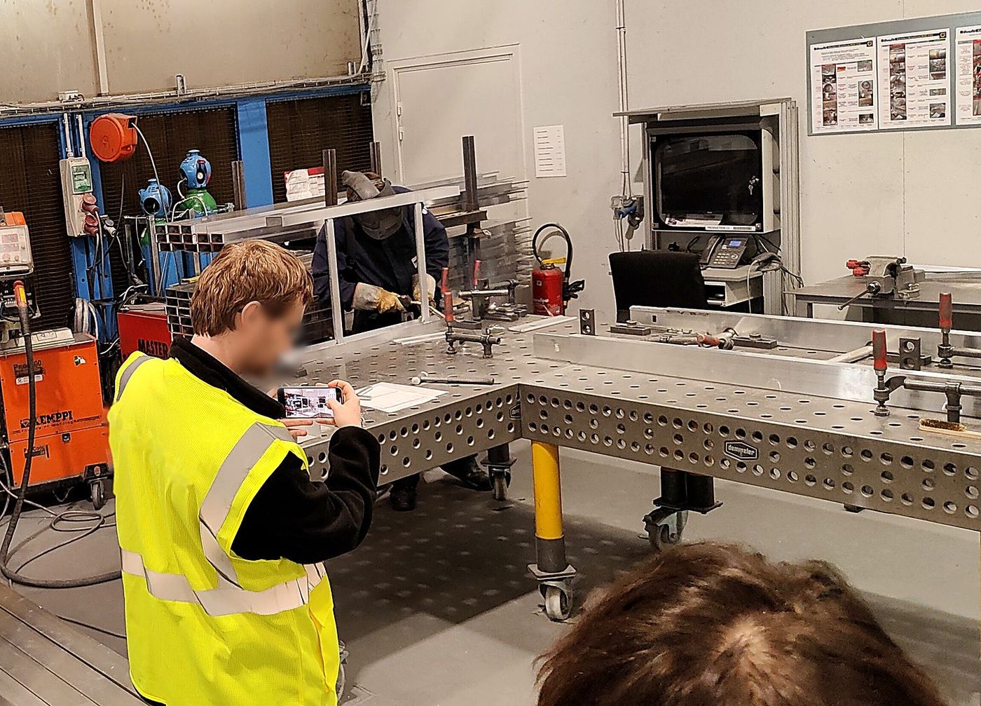 Un membre d'une équipe communication filme une opération de production avec son téléphone